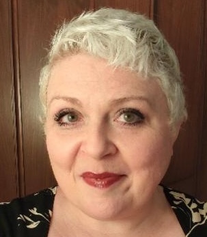 A smiling woman with short blond hair looking at the camera