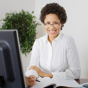 Older African American woman smiling at desk in front of computer.