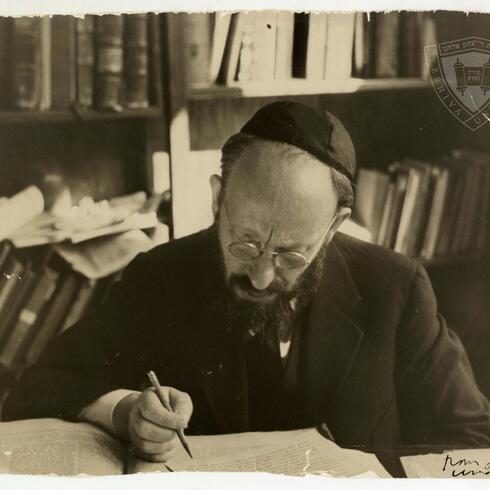 Rabbi Dr. Bernard Revel seated at a desk. There are bookshelves in the background.
