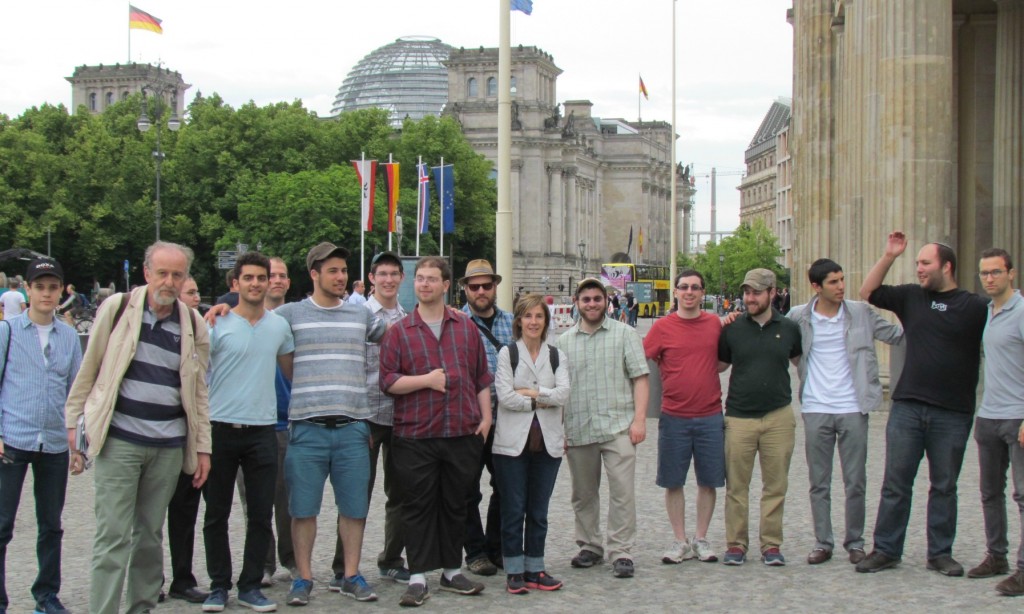 Students in a plaza across the street from the Holocaust memorial. In the background is the ceiling of the Bundestag (the German Parliament) and part of the Brandenburg Gate.