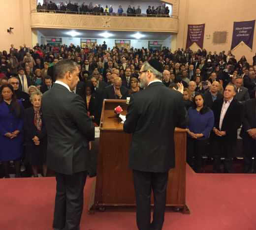 Rabbi Ezra Schwartz, right, rosh yeshiva at YU's Rabbi Isaac Elchanan Theological Seminary, delivers the opening benediction at the New York swearing-in ceremony of x. 