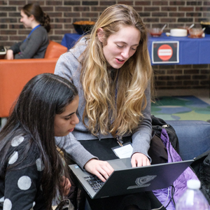 Two women coding on computers
